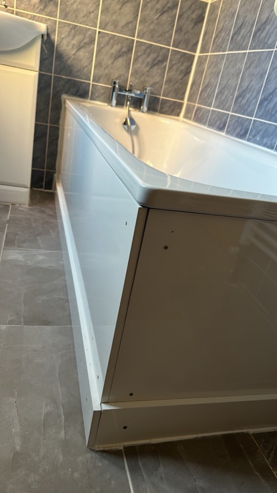 A white bath with a new front panel and chrome bath-filler tap fitted against slate-blue tiling by Capital Flow Heating and Plumbing.