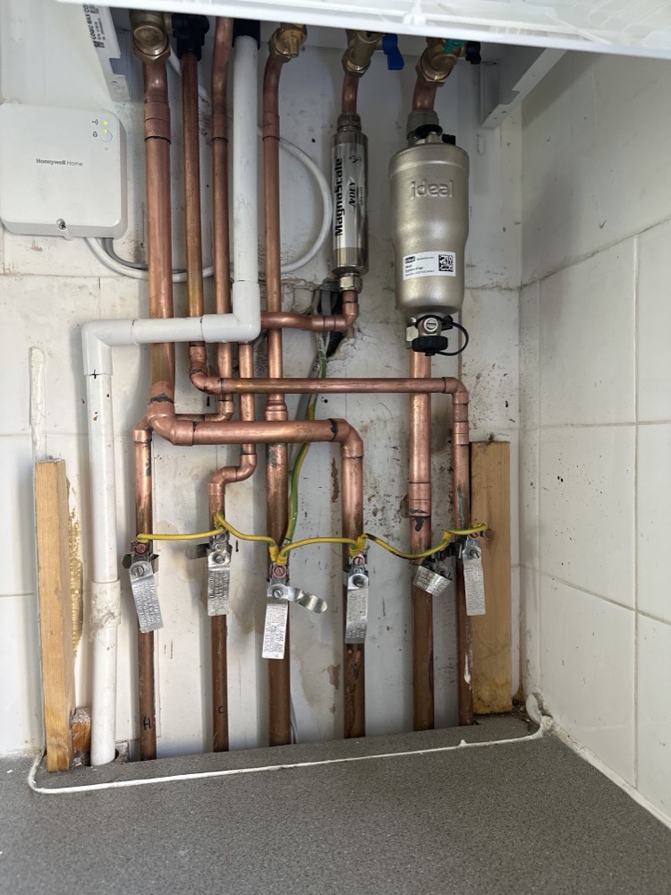 Copper pipework, an Adey MagnaScale and an Ideal system filter fitted beneath a boiler by Capital Flow Heating and Plumbing, with a Honeywell Home controller.