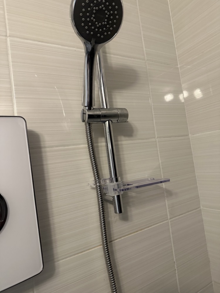 Close-up of a chrome shower riser rail, handset and soap dish neatly fitted on tiled bathroom wall by Capital Flow Heating and Plumbing.